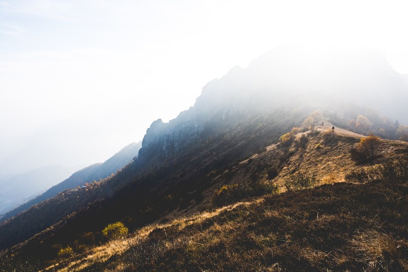 a jagged mountain with its peak bathed in bright sunlight, blinding light over the mountaintop 4k