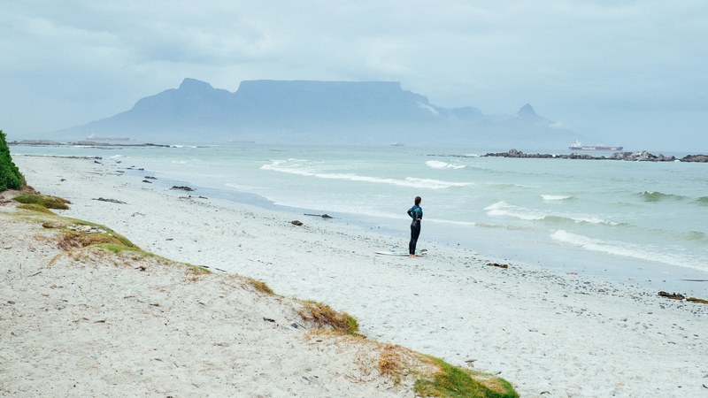 woman surfer standing on the beach in table view looking at the ocean, surfer looking at the ocean 4k