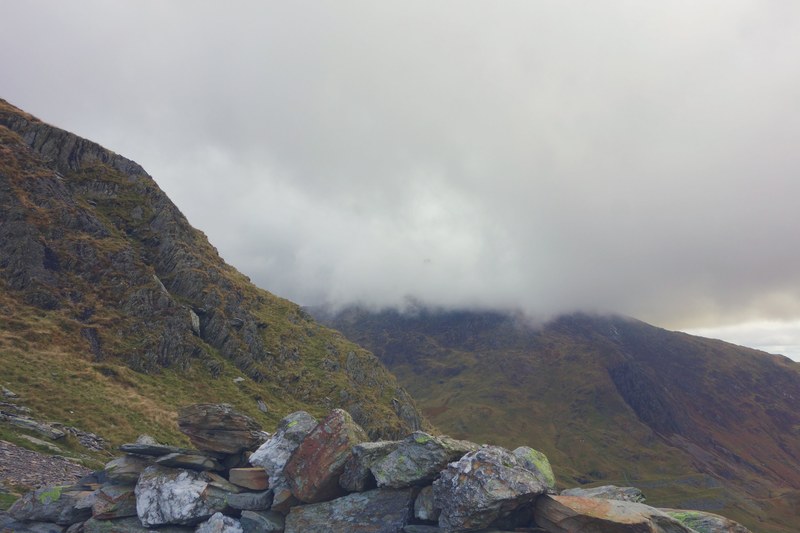 a pile of rocks on a mossy mountain slope near snowdon, clouds over green mountains in scotland 4k