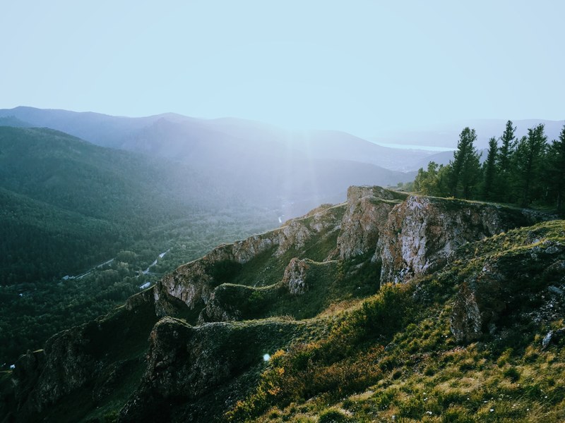 a rocky slope over a green valley in russia, jagged rocks over a valley 4k