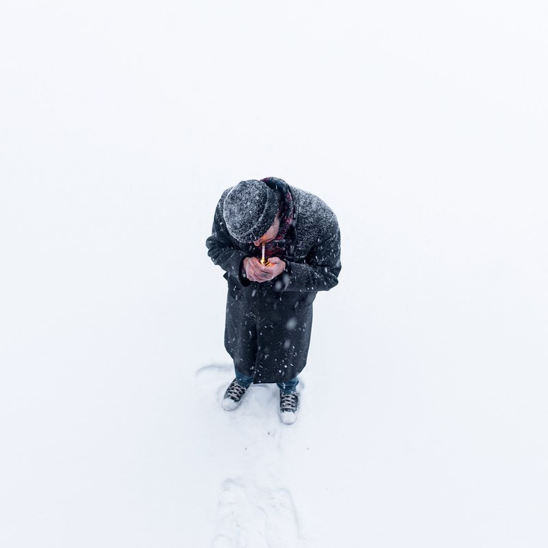 a man covers his cigarette and lighter with his hand to light his smoke on a cold winter day, lighting cigarette in winter 4k