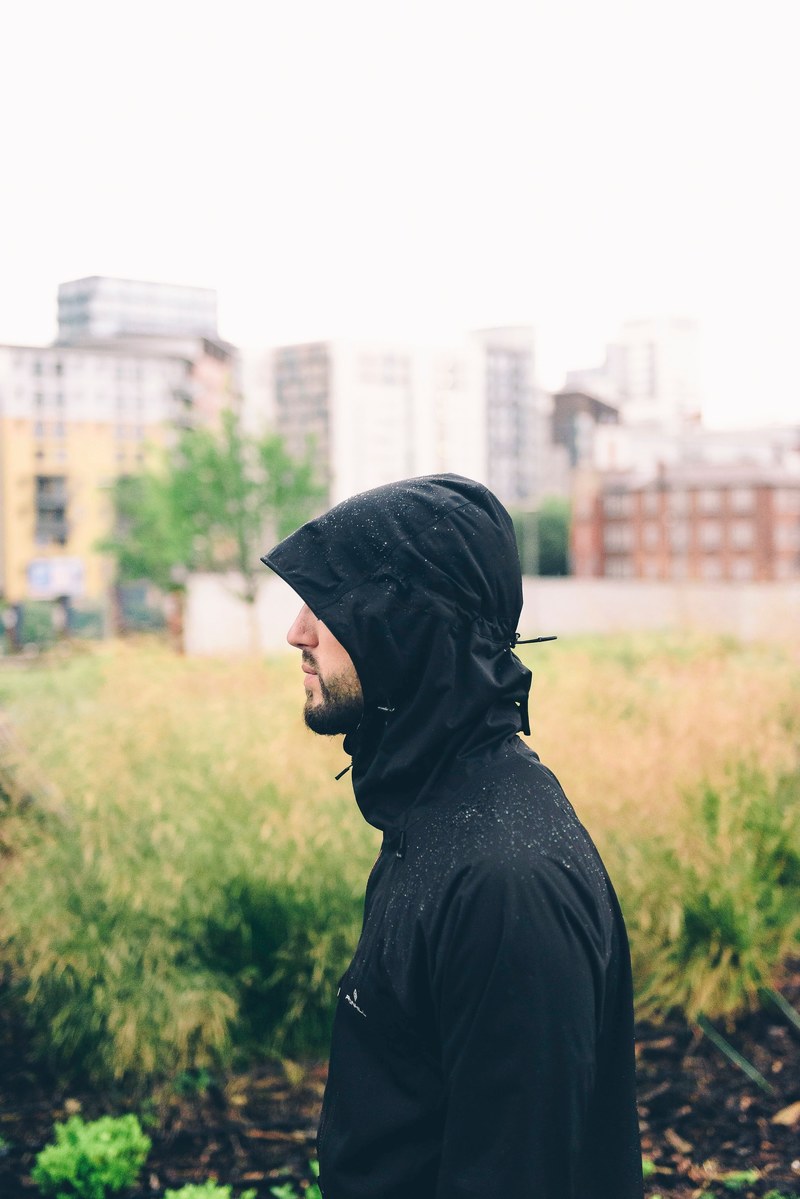 profile of a man in a black hooded raincoat outside, jacket with a hood 4k