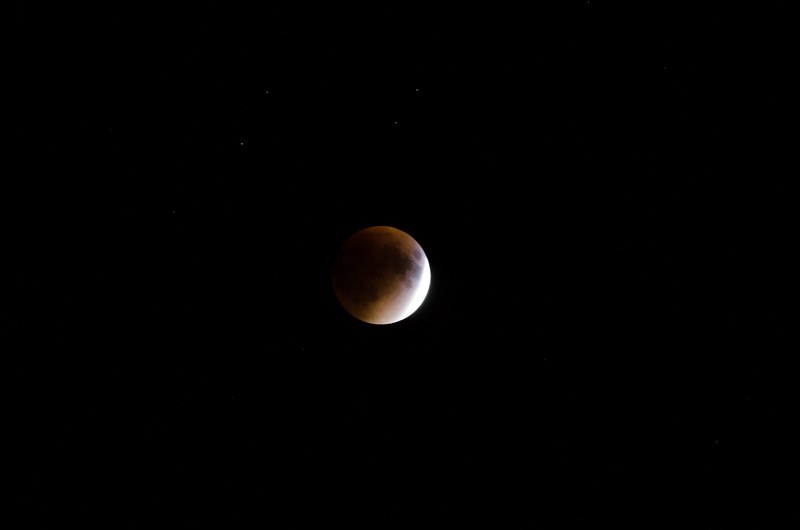 red moon and stars on the night sky, lunar eclipse in the making 4k