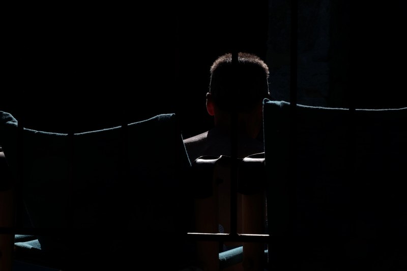 a dim shot of a silhouette of a man behind bars, darkness behind bars 4k