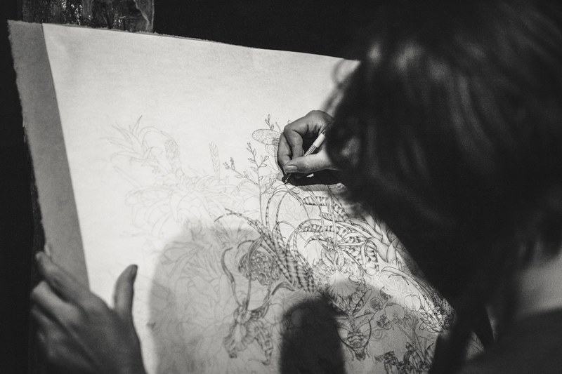black and white shoulder shot of artist sketching an illustration on easel, artist drawing 4k