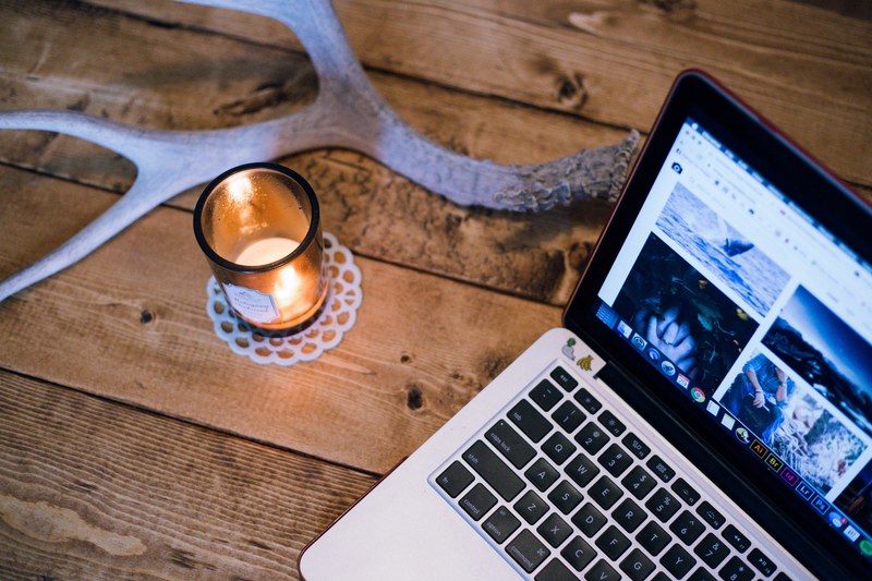 a lit candle and an antler on a table next to a laptop, candle antler and laptop 4k