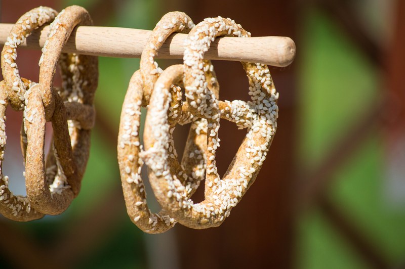 four pretzels covered in sesame seeds on a wooden pole in novi sad, pretzel pole 4k