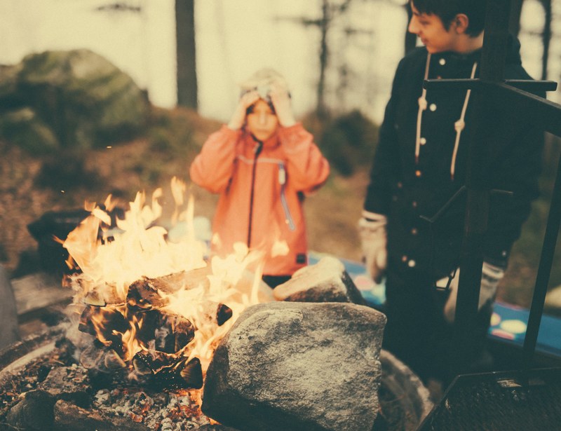 a child and teenager stand near a fire in bors, stand by the fire 4k