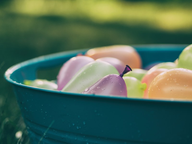 multicolored water balloons in a bucket outdoors, water balloons in bucket 4k