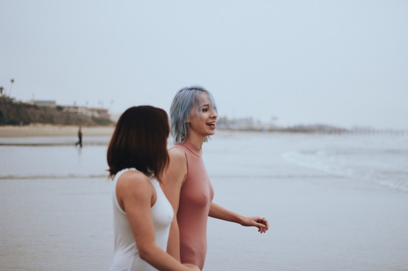 two women in swimsuits talking at the sand pismo beach, beach vibes 4k