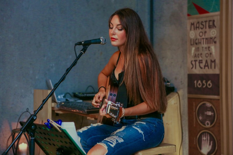 a dark haired woman in ripped jeans playing acoustic guitar, woman with acoustic guitar 4k