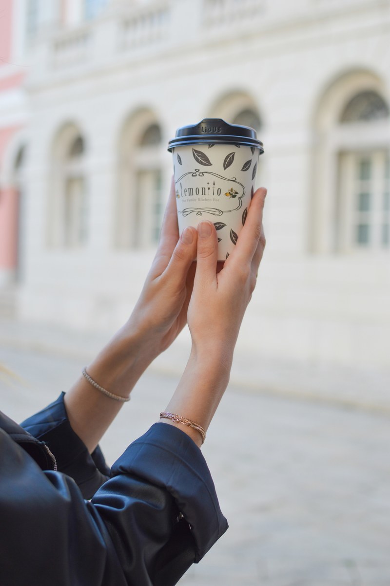 a woman holding up a takeaway coffee cup, coffee cup in womans hands 4k