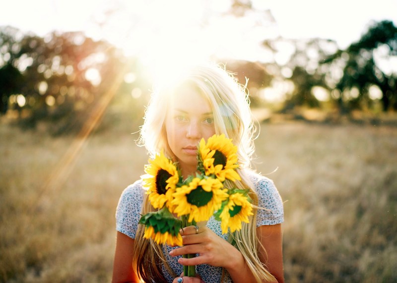 a blonde woman holding a bunch of young sunflowers, woman with sunflowers 4k