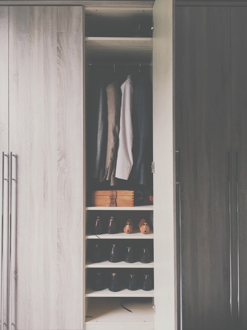 a monochromatic wooden closet with silver handles filled with shoes a wooden box and suit jackets in wilmslow england united kingdom, wilmslow uk closet 4k