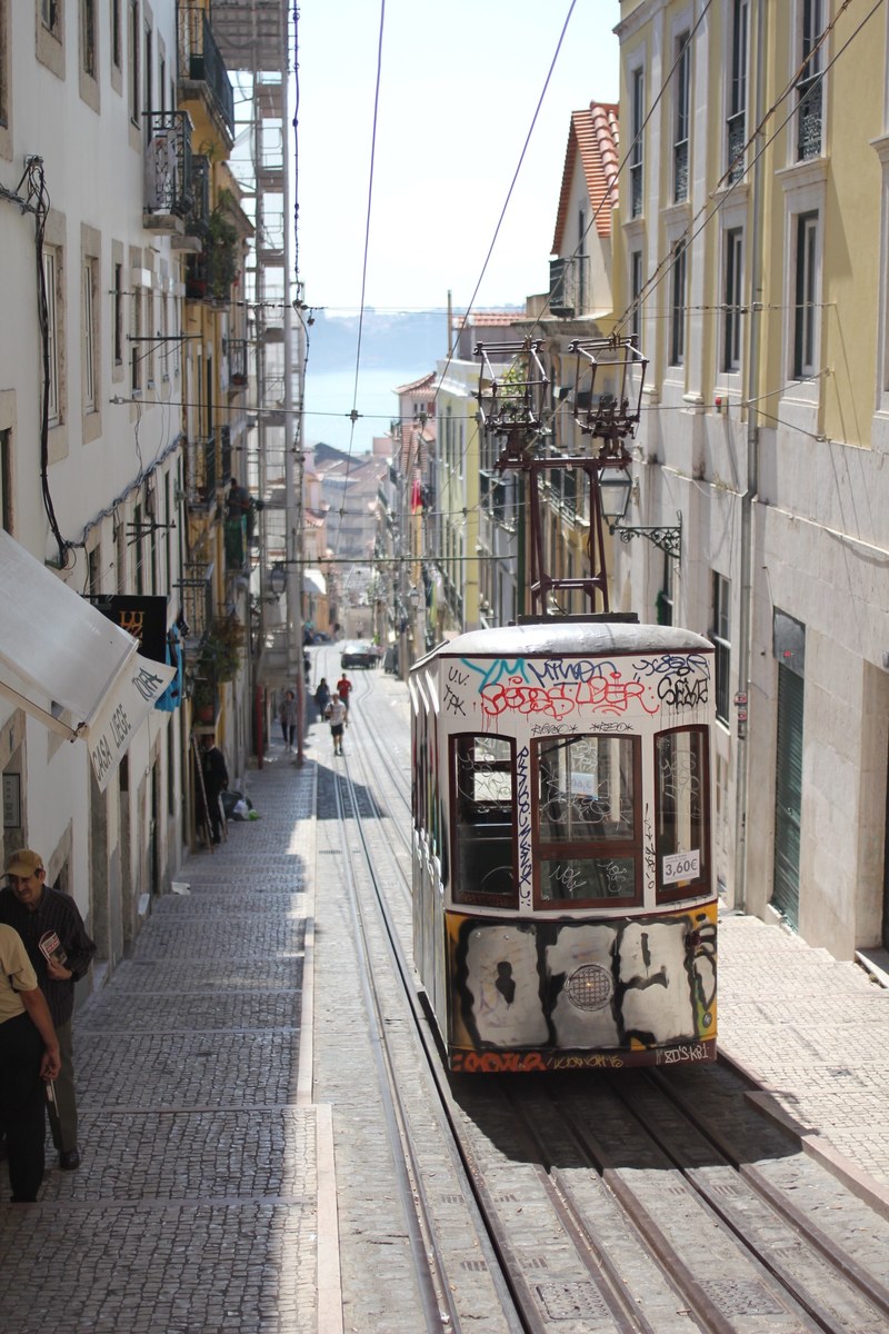 abandoned street tram filled with graffiti sitting stationary in a lisbon street as people walk by, tram in lisbon 4k