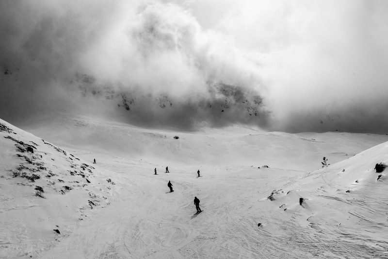 a silhouette black and white image of skiers on a sloped hill in brezovica kosovo, mist 4k