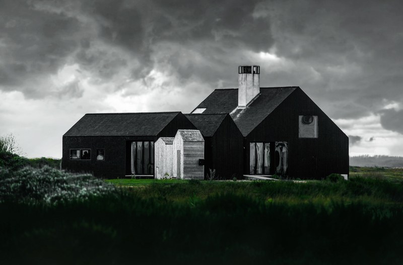large cabin like wooden house with white sheds and chimneys on a grassy hill, storm retreat 4k