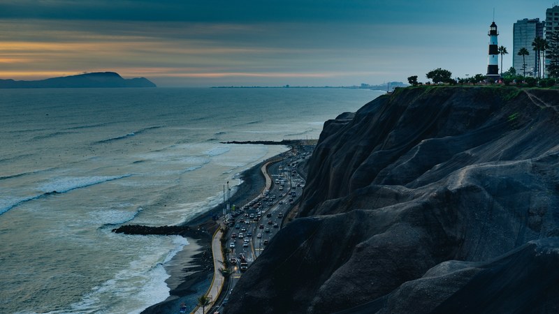 la marina lighthouse in miraflores peru standing upon a rocky cliff during sunset as waves crash on the shoreline, la marina lighthouse cliffside 4k