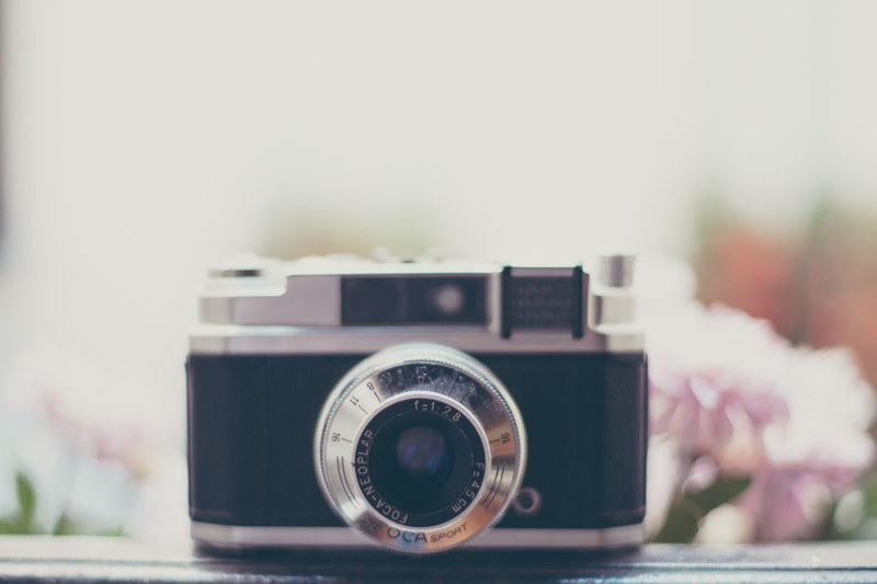 close up of a vintage camera with pink flowers in the blurry background, vintage camera and flowers 4k