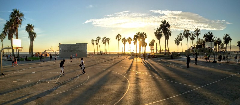 two men playing basketball outside in venice beach during the late sunset, outdoor basketball with sunset 4k