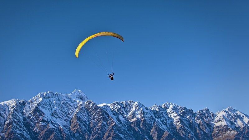 a paraglider soaring over snowy mountains, soaring paraglider 4k