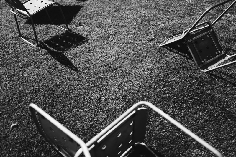 black and white photo of fallen chairs on grass with shadow, fallen chairs on grass 4k