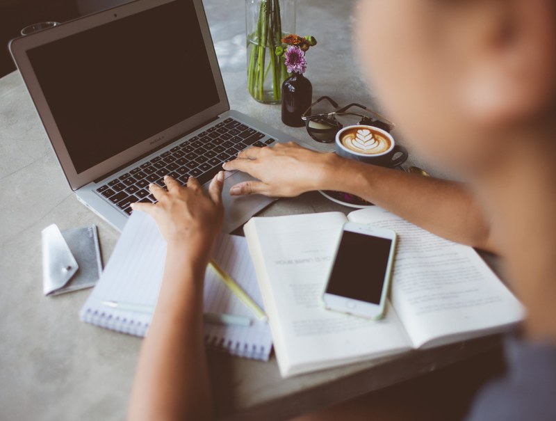 a person typing on a macbook keyboard with a book and a smartphone next to it, writer at work 4k