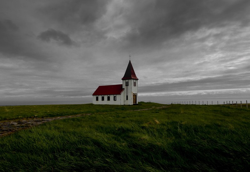 a white church building in the middle of farmland near the ocean covered by gray clouds, _lonely church in iceland 4k