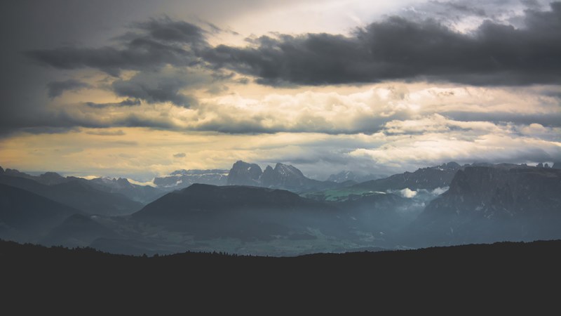 a breathtaking panorama with tall mountains and green valleys below gray clouds, clouds over the mountains 4k