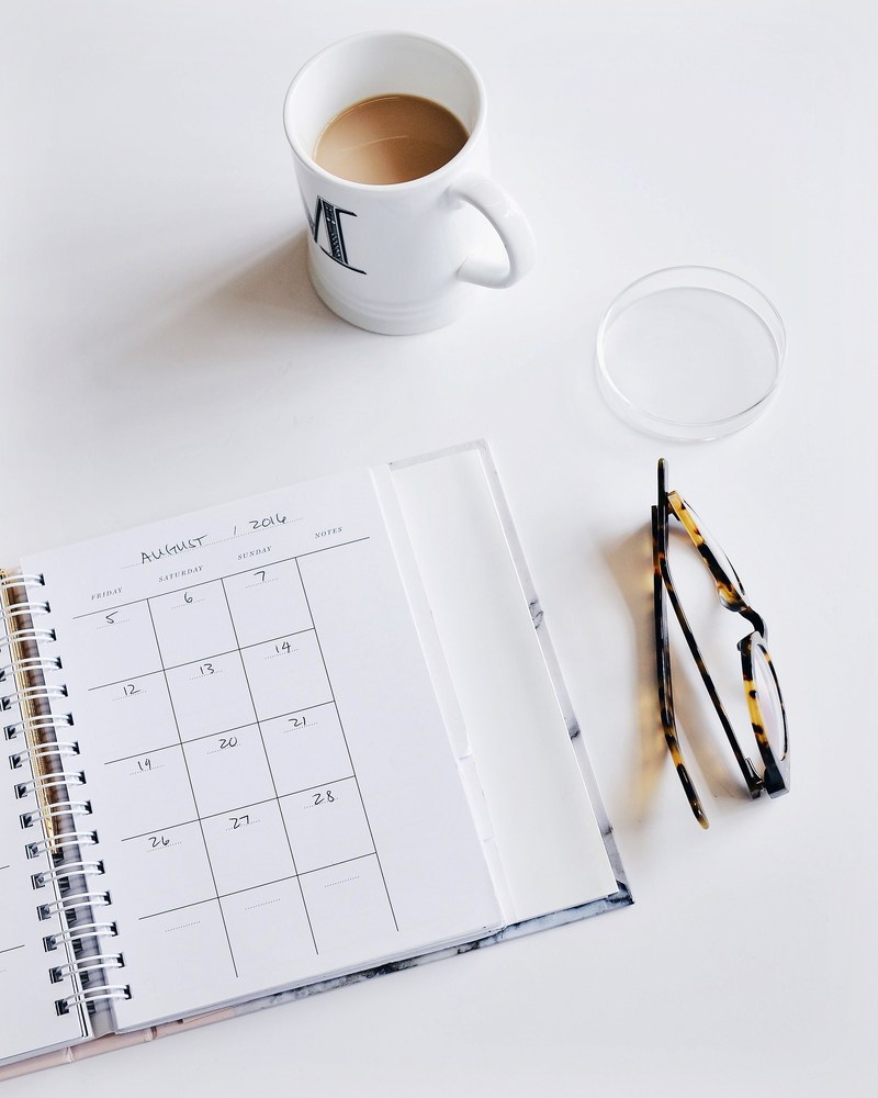 a calendar book pair of glasses and cup of coffee on a white surface, _planning with a cup of coffee 4k