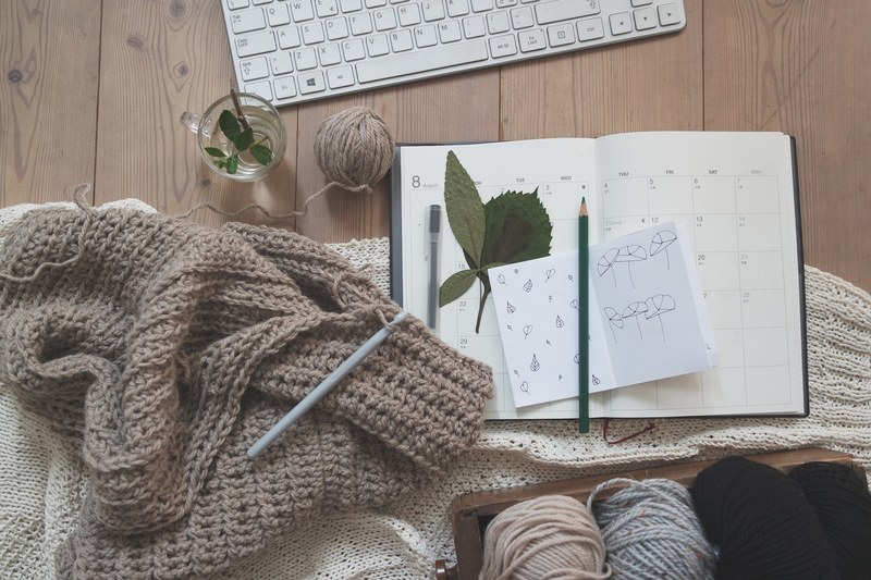 a piece of paper covered with doodles next to yarn balls and a crocheting kit, crochet tools notebook 4k