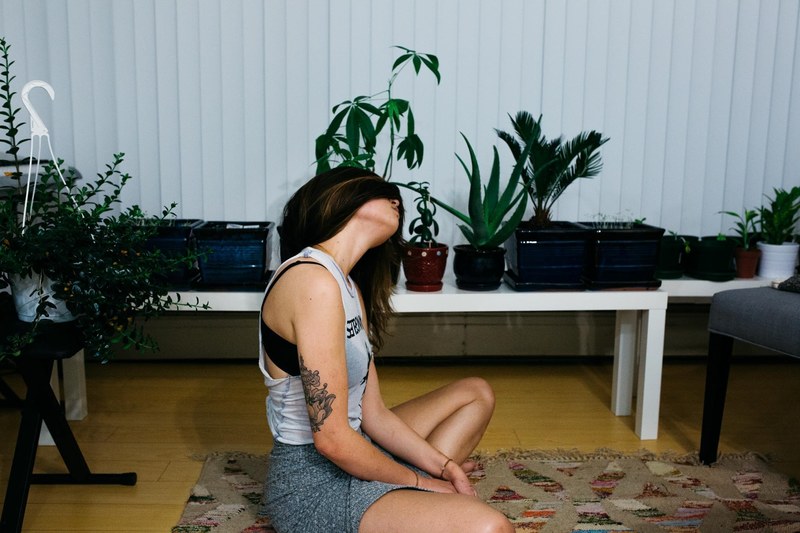 a brunette woman doing yoga in her living room that is filled with plants, at home yoga 4k