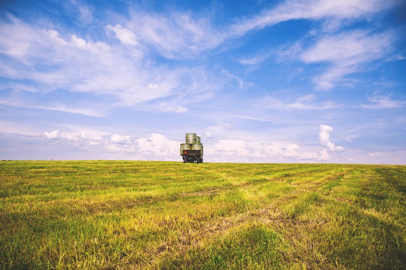 a green field and a truck driving off into the horizon where it meets the blue skies in suchawa, suchawa farmland 4k