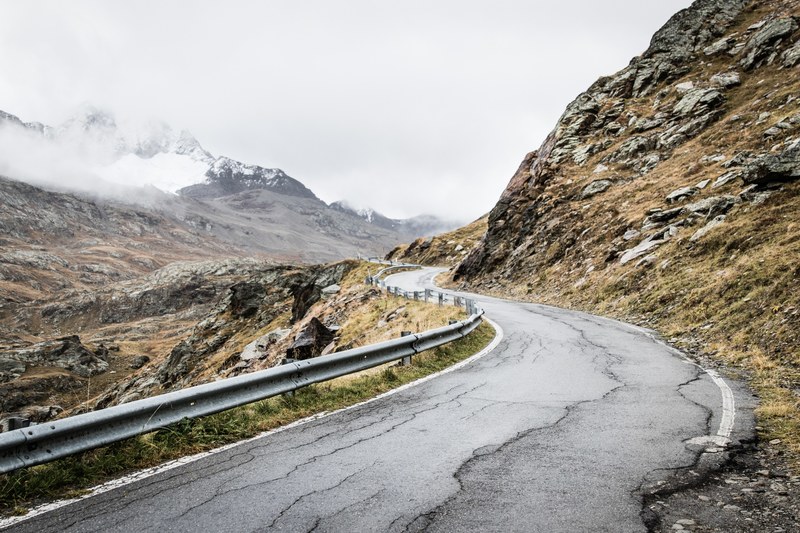 rural country road winds around a rocky mountainside, old mountain road 4k