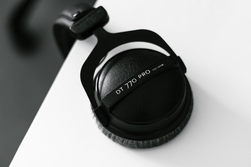 close up of black headphones hanging from a white surface, top view of headphones hanging from a desk 4k