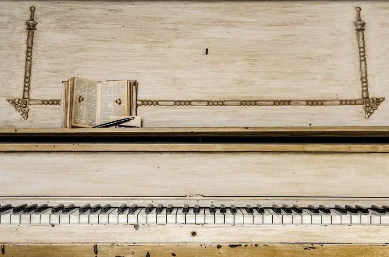 a worn out beige piano with a little booklet and a pen on it, worn out white piano 4k