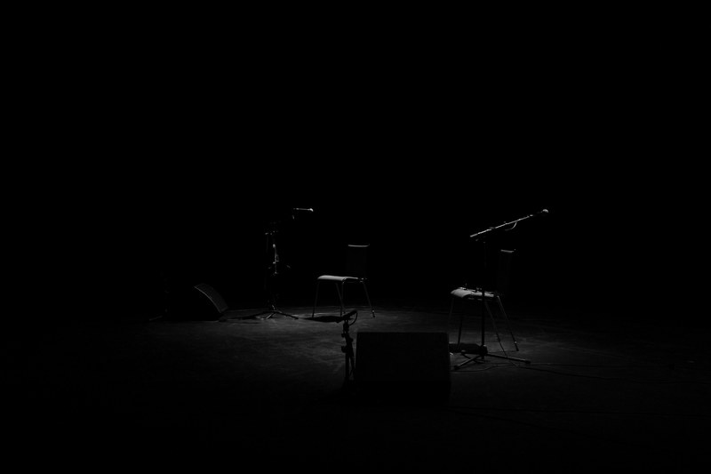 a dim shot of two chairs and microphone stands on an empty stage, empty stage at night 4k