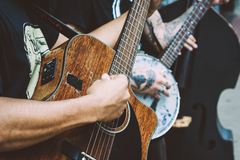 a close up of a mans hand clutching a pick and playing a worn out acoustic guitar, my first guitar 4k