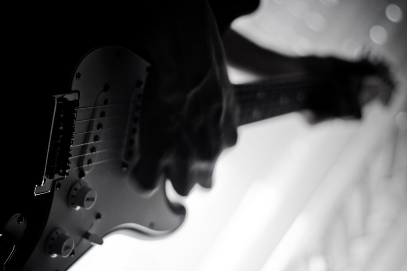 a low angle black and white shot of a person playing an electric guitar, guitarist in black and white 4k
