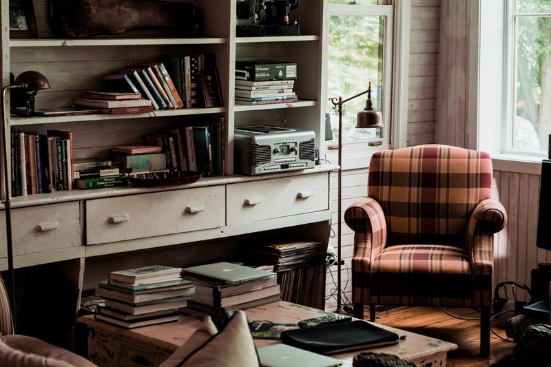 living room interior filled with books on the table and bookshelf with a plaid chair, books in living room 4k