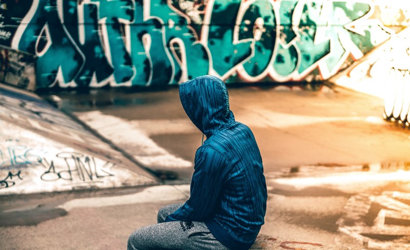 anonymous skater in a hoodie sits in a skate park, masked 4k