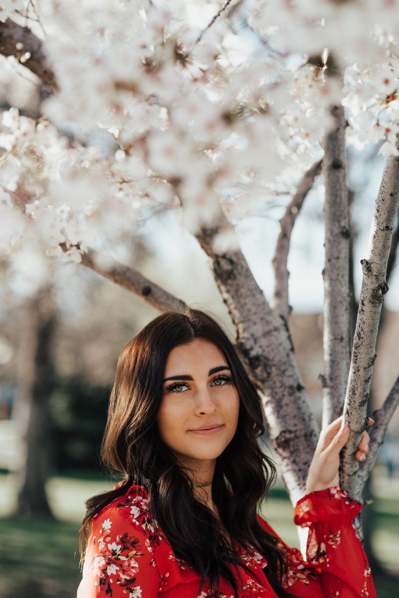 woman simling softly in a red dress by a cherry blossom tree, blossom beauty 4k