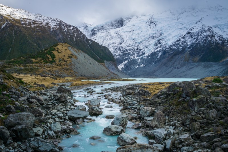 an azure stream on a rocky bed in the mountains, hiking up to lake view of mount cook 4k