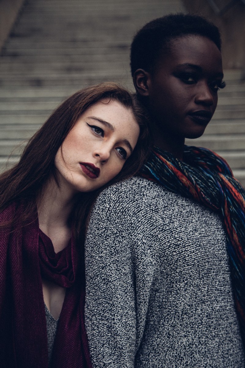 fashionable women leaning on each other pose by a staircase, leaning on each other 4k