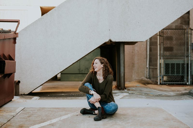 a woman laughing while sitting on a concrete floor, laughing woman on the floor 4k