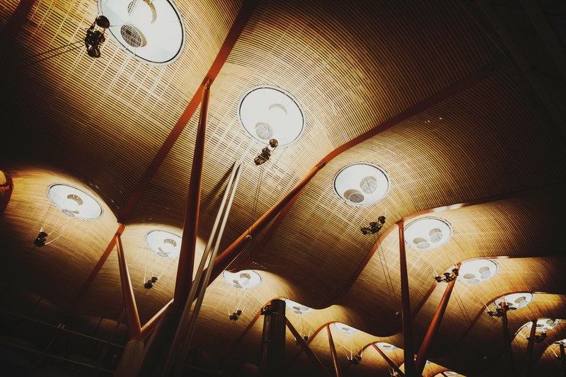 a large curved design ceiling with lights and v shaped wooden posts, large ceiling 4k