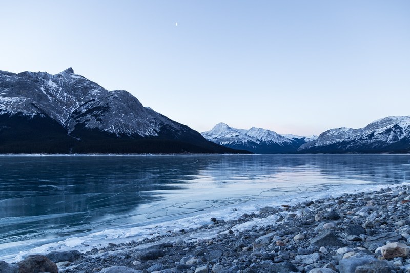 an icy gray lake by snowy mountains of nordegg in alberta canada, into the north 4k