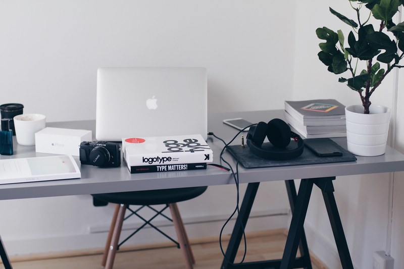 books about typography on a busy desk with a macbook a camera and smartphones, setup 4k