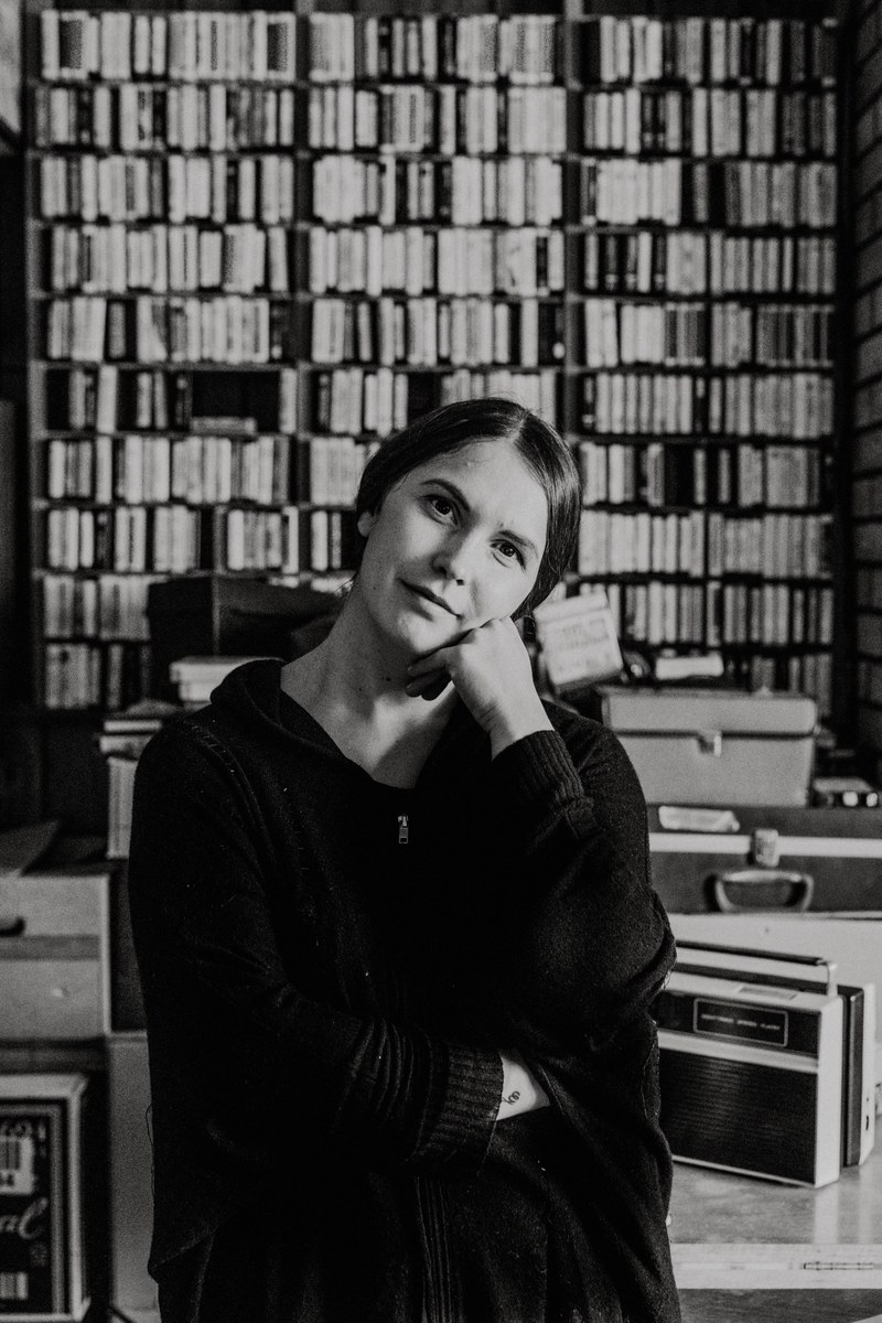 a woman sitting bored in a library with her fist against her jaw, _bored woman in library 4k