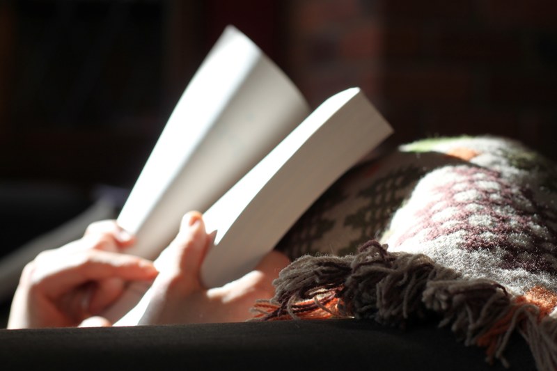 a person reading a book under a blanket, getting cozy with a book 4k
